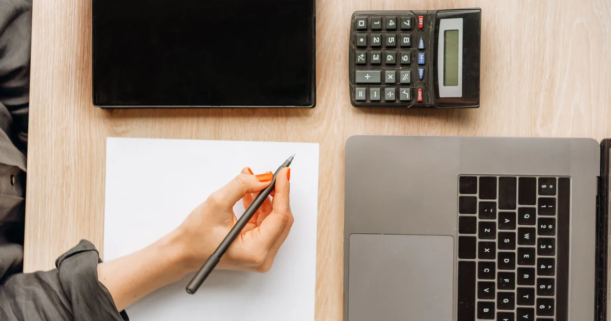 A desk with paperwork, a calculator and a keyboard